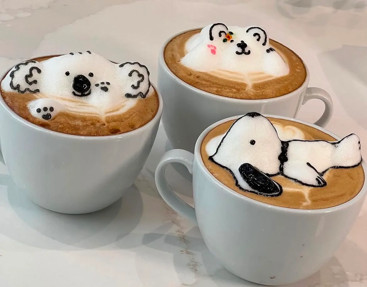 Tres cafés con arte latte 3D en la espuma: un koala, un osito y el perrito Snoopy